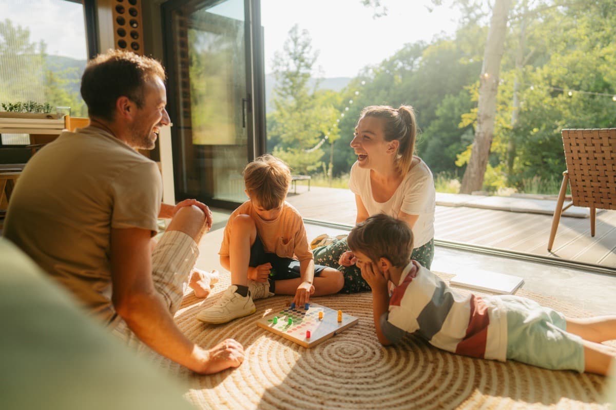 Young professional's family laughing together while playing a board game on the floor